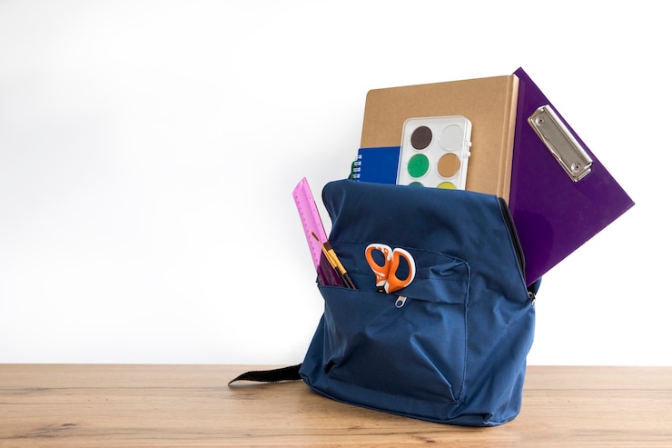 Photo gratuit un sac à dos bleu avec des fournitures scolaires