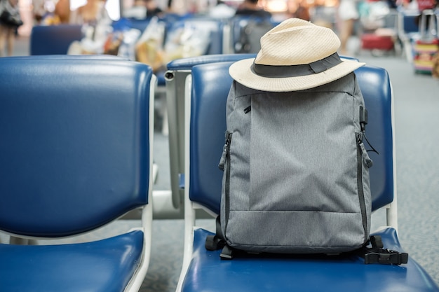 Sac à dos gris avec chapeau sur le siège à l'intérieur du terminal de l'aéroport. business et concept de voyage