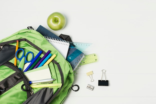 Photo gratuite sac à dos ouvert avec accessoires d'école vue de dessus