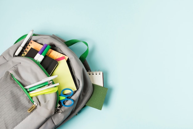 Photo gratuite sac à dos ouvert avec fournitures scolaires