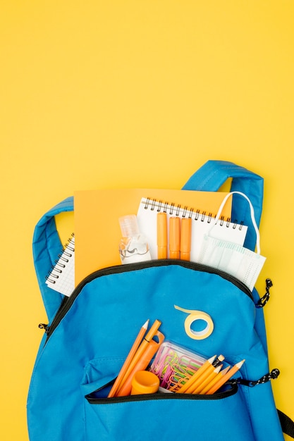 Photo gratuite sac à dos plat avec fournitures scolaires
