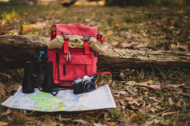 Photo gratuite sac à dos rouge hipster et carte dans la forêt