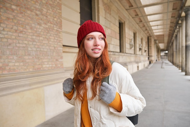Photo gratuite sac à dos touristique happy redhead girl promenades en ville avec un sac part en voyage explore la ville porte du rouge ha