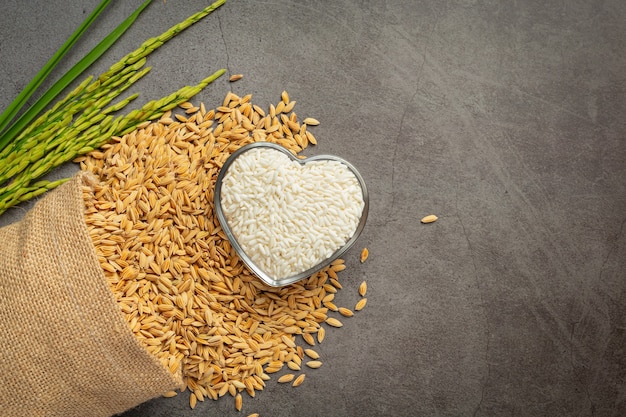 Un sac de graines de riz avec du riz blanc sur un petit bol en verre et un plant de riz