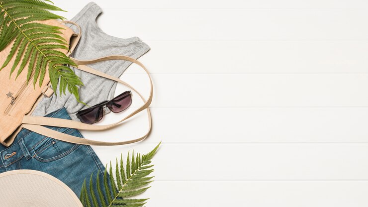 Photo gratuit sac à main près de lunettes de soleil avec des brindilles d'usure et de plantes