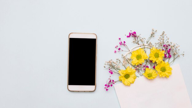 Sac en papier décoré de fleurs et smartphone sur fond blanc