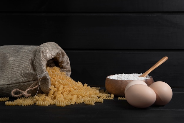 Un sac plein de fusilli de pâtes sèches crues avec de la farine et des œufs de poule. Photo de haute qualité