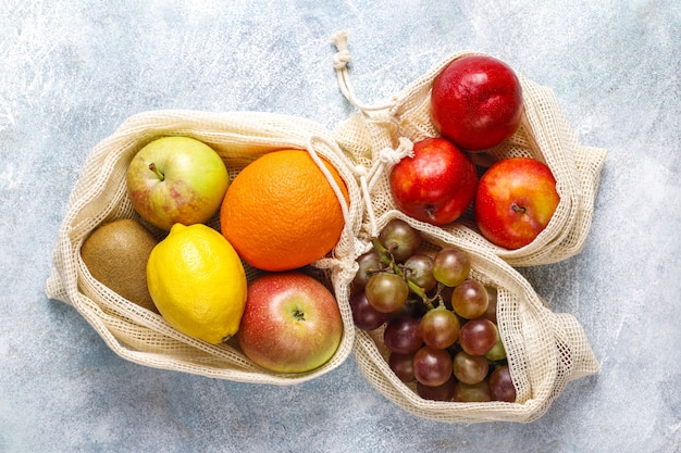 Photo gratuite sacs à provisions écologiques simples en coton beige pour acheter des fruits et légumes avec des fruits d'été.