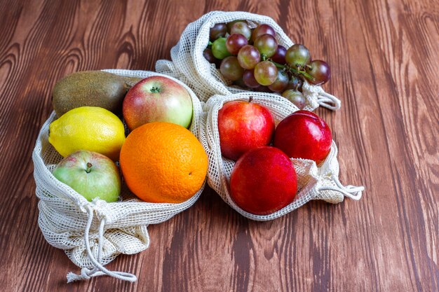 Sacs à provisions écologiques simples en coton beige pour acheter des fruits et légumes avec des fruits d'été.