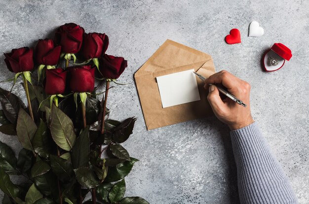 Saint-Valentin main d&#39;homme tenant un stylo écrit lettre d&#39;amour avec carte de voeux