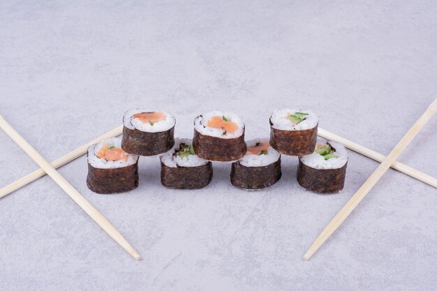 Saké maki roule sur fond gris avec des baguettes