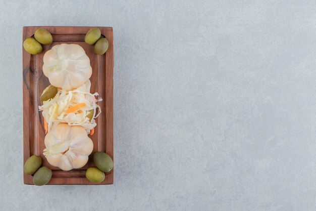 Salade d'ail et de choucroute aux olives sur la plaque en bois sur la surface en marbre