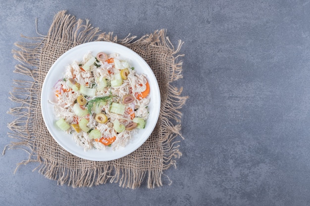 Salade appétissante au poulet sur plaque blanche.