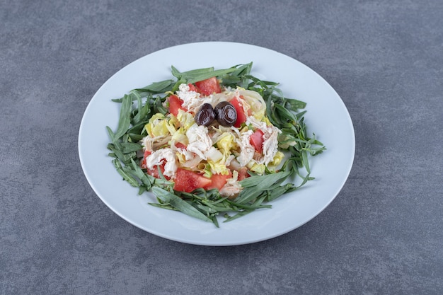 Salade appétissante fraîche sur plaque blanche.