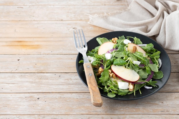 Salade d'automne avec des pommes et des noix sur une table en bois