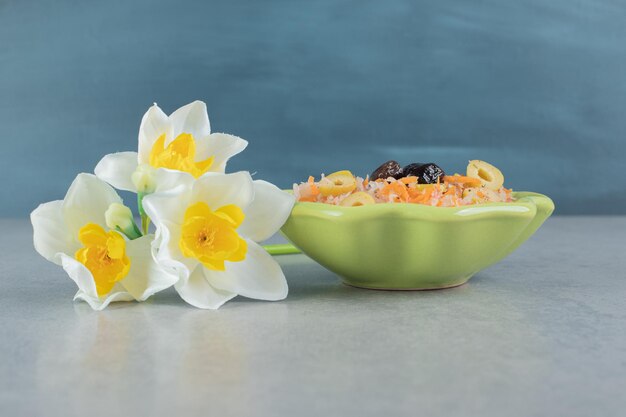 Salade de carottes de couleur orange avec des ingrédients mélangés dans une assiette verte.