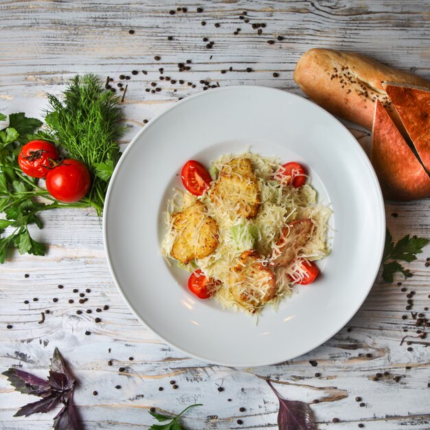 Salade César dans une assiette avec tomate, pain, herbes et épices