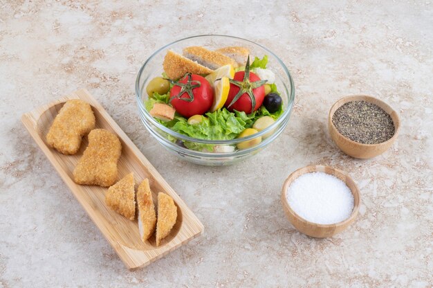 Salade César avec nuggets de poulet, herbes et tomates cerises.