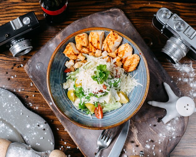 Salade César avec poulet et parmesan dans un bol sur une table en bois