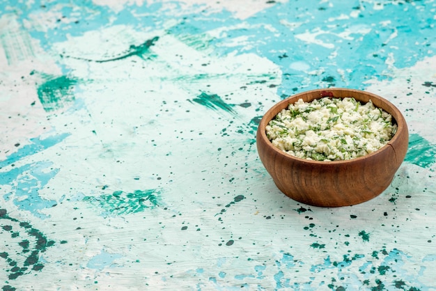 Photo gratuite salade de choux frais tranchés avec des verts à l'intérieur d'un bol brun sur un bureau bleu vif