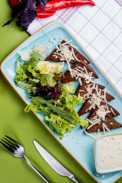 Salade avec côté pain noir garni de fromage