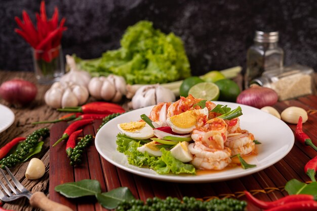 Salade de crevettes avec laitue aux œufs durs et oignons verts hachés dans une assiette blanche