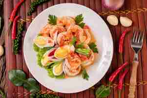Photo gratuite salade de crevettes avec laitue aux œufs durs et oignons verts hachés dans une assiette blanche
