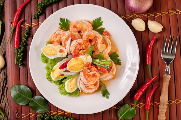 Salade de crevettes avec laitue aux œufs durs et oignons verts hachés dans une assiette blanche