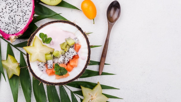 Salade de fruits dans une assiette de noix de coco avec cuillère