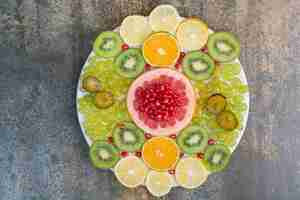 Photo gratuite salade de fruits à la grenade, pamplemousse et kiwi sur plaque blanche. photo de haute qualité