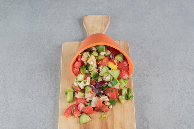 Salade de fruits et légumes hachés sur une planche de bois.