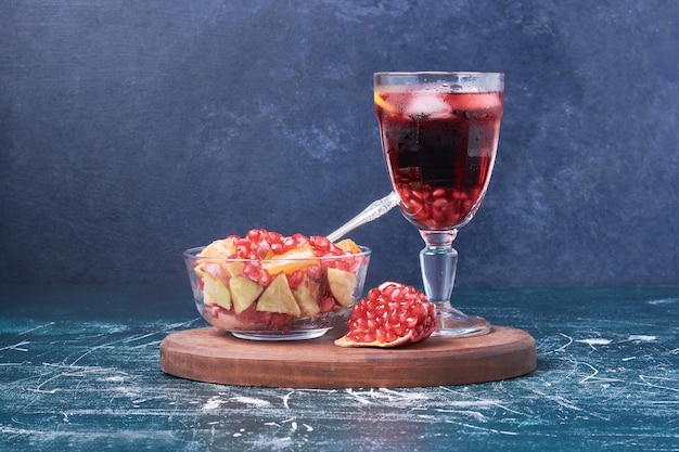 Salade de fruits avec une tasse de boisson sur bleu.