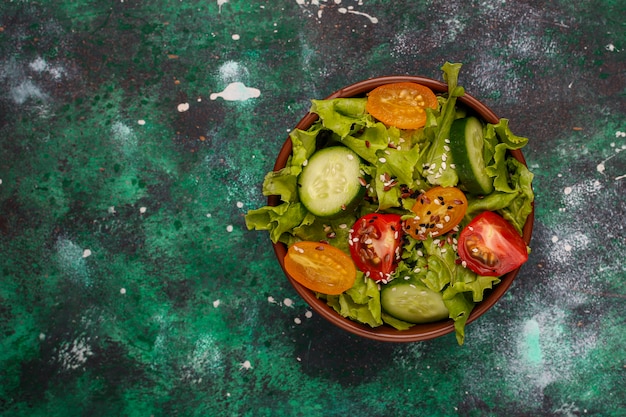 Photo gratuite salade de laitue fraîche avec tomates jaunes, tranches, tomates cerises, bol de graines à la noirceur,