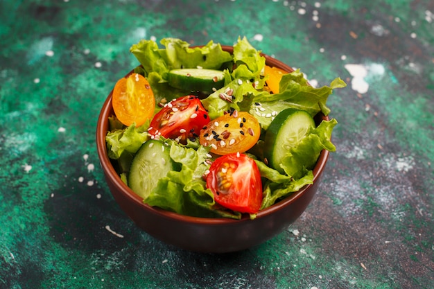 Photo gratuite salade de laitue fraîche avec tomates jaunes, tranches, tomates cerises, bol de graines à la noirceur,