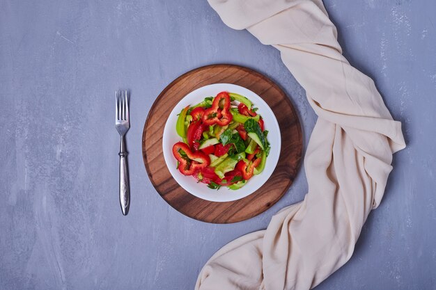 Salade de légumes dans une assiette blanche sur bleu