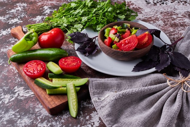 Salade de légumes dans une tasse en bois servie avec des herbes.