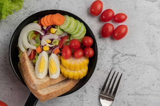 Salade de légumes avec du pain et des œufs durs dans la poêle.