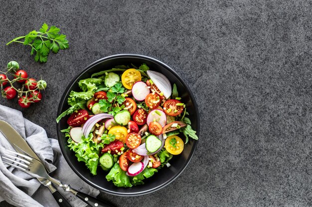 Salade de légumes frais dans une assiette sur fond noir. Vue de dessus