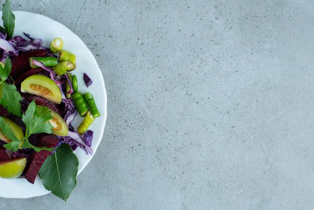 Salade de légumes frais sur plaque blanche.