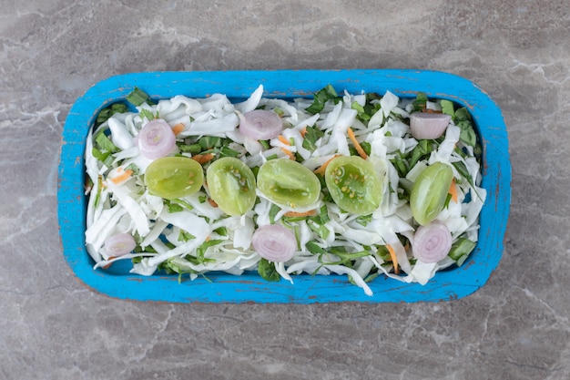 Salade de légumes frais sur plaque bleue.