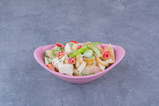 Salade de légumes hachés et d'herbes sur une surface bleue