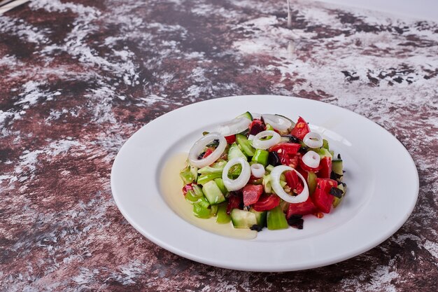 Salade de légumes avec des ingrédients hachés et hachés dans une assiette blanche, vue d'angle.