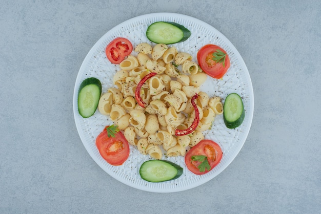 Salade de légumes sur plaque blanche avec de délicieux macaronis sur fond de marbre