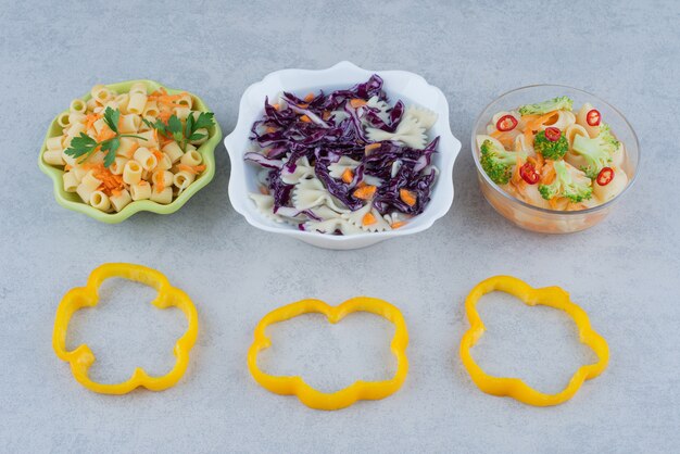 Salade de légumes sur plaque blanche avec macaroni sur surface en marbre