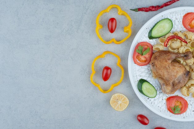 Salade de légumes sur plaque blanche avec pâtes et poulet sur fond de marbre