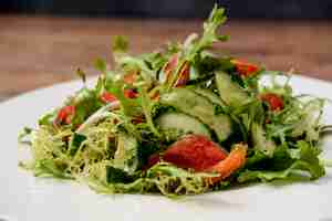 Photo gratuite salade de légumes en plaque ronde blanche sur table en bois.