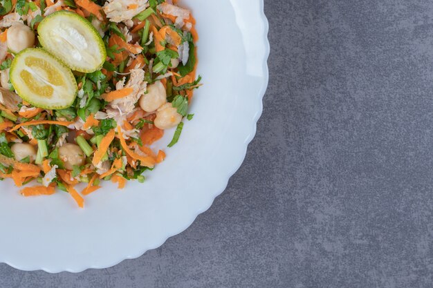 Salade de légumes savoureuse sur plaque blanche.