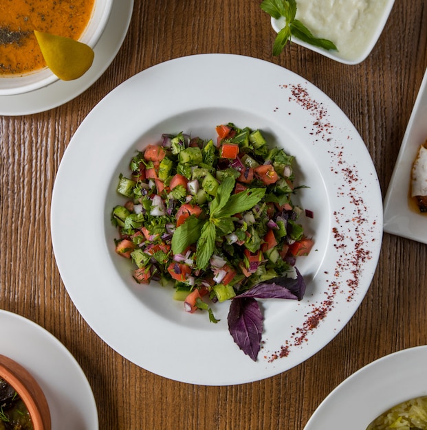 Salade de légumes verts vue de dessus avec les cubes à l'intérieur de la plaque blanche.