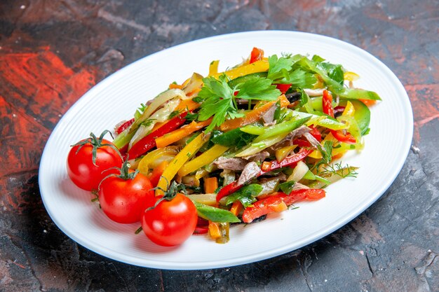 Salade de légumes vue de dessous sur une assiette ovale sur une surface sombre