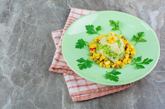 Salade de maïs sur une assiette sur un torchon, sur le marbre.